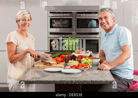 Man & woman couple préparation des sandwichs sains à la maison cuisine avec jambon, fromage, salade de laitue et tomates Banque D'Images