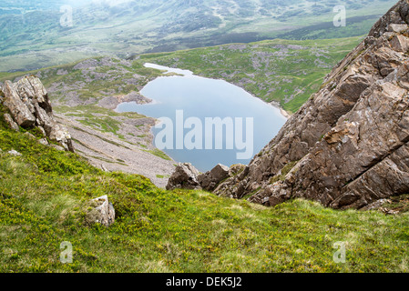 À la recherche du haut de la montagne Cadair Idris dans le parc national de Snowdonia sur Llyn y Gader avec cloudy stormy Summer Sky landscape Banque D'Images