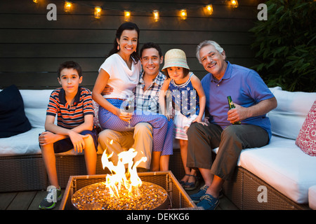 Family smiling autour d'un foyer en plein air Banque D'Images