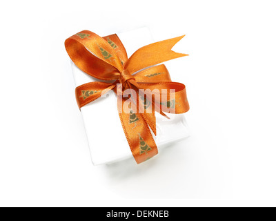 Enveloppé d'un cadeau de Noël avec un ruban d'or colorés et noeud sur un fond blanc. Banque D'Images