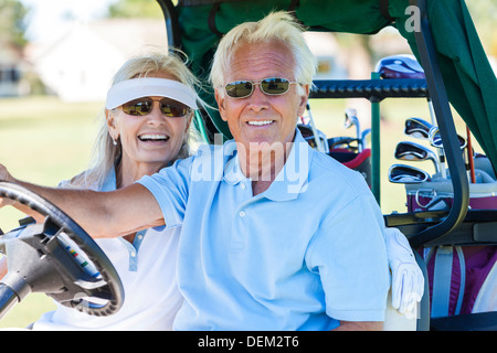 Happy senior man and woman couple ensemble jouant le golf conduisant le chariot de golf ou buggy sur le cours Banque D'Images