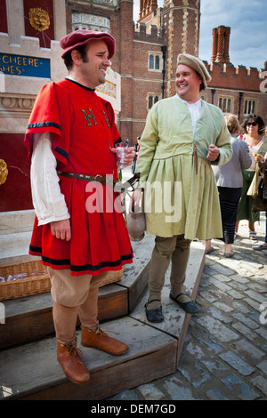 Acteurs en costume de main verres de vin à l'Henry VIII fontaine de vin de base en cour à Hampton Court Palace. Banque D'Images