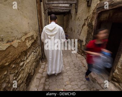 Vue arrière d'un homme portant une djellabah traditionnelle dans une ruelle de la médina de Fez, Maroc Banque D'Images