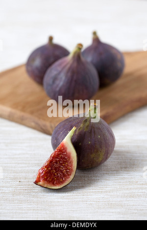 Ficus carica. Cinq figues Bursa noir sur une planche de bois. Banque D'Images