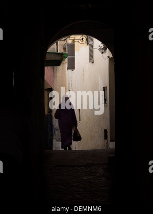 Silhouette de femme arabe avec hijab marcher dans une ruelle sombre à Tanger, Maroc Banque D'Images
