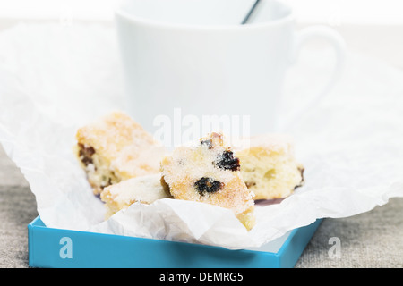 Petits gâteaux traditionnels stollen allemand dans du papier parchemin en face d'une tasse blanche Banque D'Images