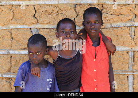 AXIM, GHANA - 13 novembre - Deux filles et un garçon posent devant un mur d'adobe dans un typique village de pêcheurs ruraux Banque D'Images