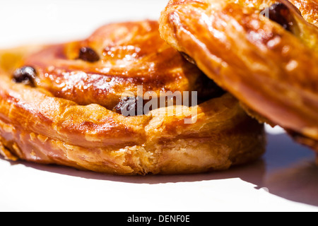 Deux délicieuses pâte pâtisserie danoise sultana's sur une plaque, à l'extérieur, sur une table au soleil Banque D'Images