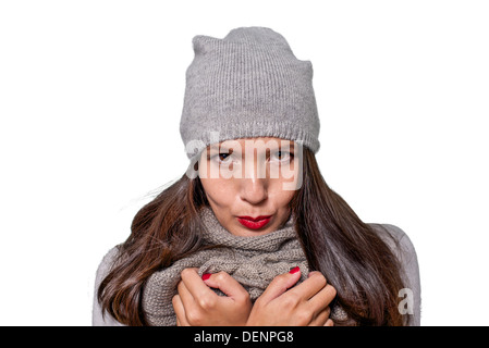 Jolie jeune femme en hiver la mode câlins à l'intérieur de son tricot jersey laineux gris, écharpe et cap sur une journée froide Banque D'Images