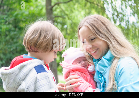 Jeune mère avec ses enfants dans la forêt. Fils est jaloux de maman plus jeune soeur. Banque D'Images