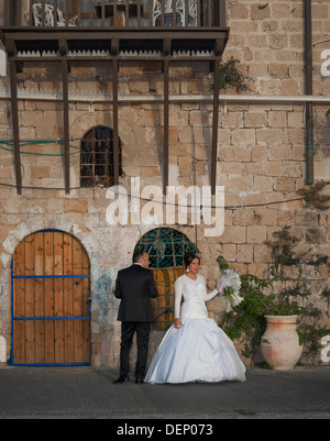 Un jeune couple le jour de leur mariage en tenant une une courte pause d'être photographiés à l'ancien port de Jaffa en Israël Banque D'Images