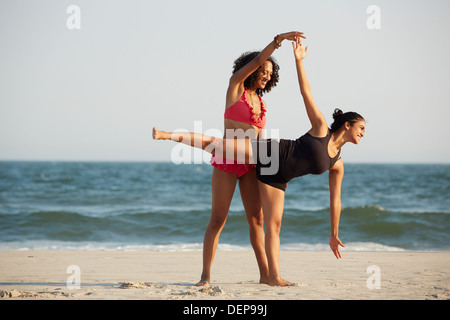 Women practicing yoga on beach Banque D'Images