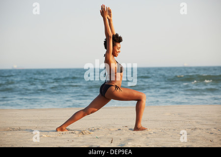 Black woman practicing yoga on beach Banque D'Images