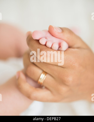 Hispanic mother holding infant's foot Banque D'Images