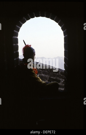 L'homme chinois habillé en guerrier mongol le regard d'une tour d'une section de Mutianyu de la grande muraille de Chine situé dans le comté de Huairou, à 70 km au nord-est du centre de Pékin. Banque D'Images