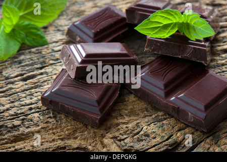 Morceaux de chocolat noir avec une feuille de menthe sur fond de bois Banque D'Images