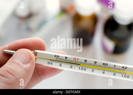 Doctor's hand holding thermomètre indiquant une température élevée Banque D'Images