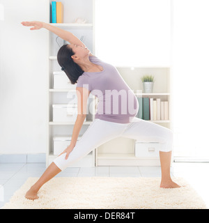 Cours de yoga prénatal. En bonne santé pleine longueur enceinte de 8 mois femme asiatique calme méditer ou faire de l'exercice de yoga à la maison. Relaxation et étirement. Banque D'Images