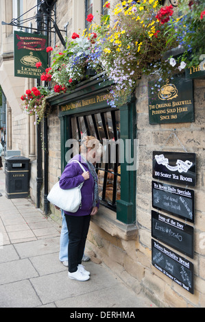 Les femmes à la recherche de la fenêtre de l'Original boutique Pudding Bakewell Bakewell Derbyshire UK Banque D'Images