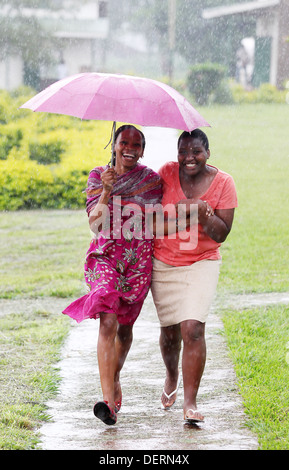 Deux jeunes filles courir à travers la pluie à leur école secondaire dans le district de Luwero en Ouganda. Banque D'Images