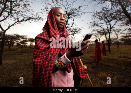 Homme Masai envoyer un message texte dans la région de Mara, Kenya, Banque D'Images