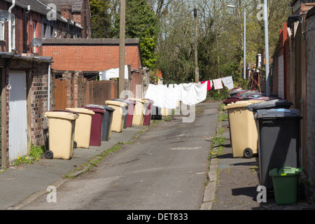 Une rue secondaire, avec séchage lavage sur la ligne et les cellules à l'extérieur, entre deux rangées de maisons mitoyennes à Bolton Lancashire Banque D'Images