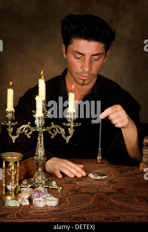 Fortune-teller holding un pendule au-dessus une photo de mariage (cette photo est le modèle libéré) Banque D'Images