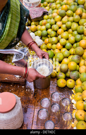 Femme indienne de vendre du jus d'orange à partir d'un panier sur une rue du village. Puttaparthi Andhra Pradesh, Inde Banque D'Images