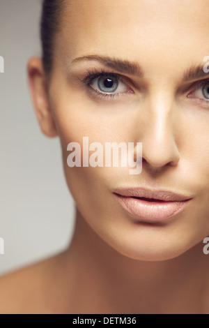 Close-up portrait de jolie jeune femme avec une peau parfaite. La moitié de visage de belle jeune femme contre l'arrière-plan gris Banque D'Images