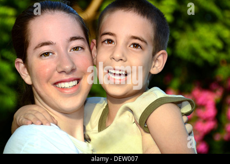 Grande soeur et petit frère appréciant la compagnie des autres et le coucher de soleil couleurs Banque D'Images