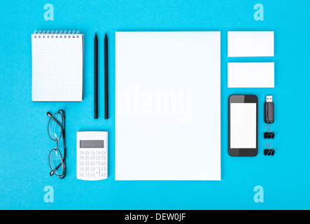 Ensemble de divers objets bureau vierge organisée pour la présentation d'entreprise ou de l'identité de l'entreprise. Isolé sur fond de papier bleu. Banque D'Images