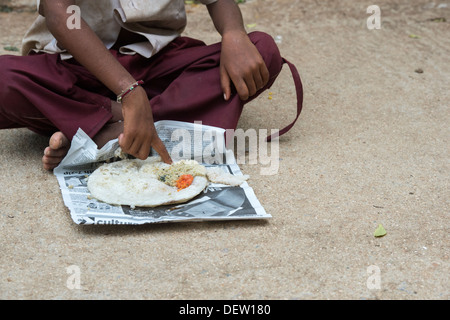 Basse caste indien boy eating dosa pour le petit-déjeuner dans une rue. L'Andhra Pradesh, Inde Banque D'Images