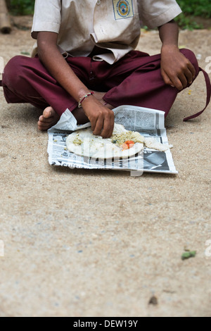 Basse caste indien boy eating dosa pour le petit-déjeuner dans une rue. L'Andhra Pradesh, Inde Banque D'Images