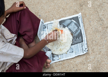 Basse caste indien boy eating dosa pour le petit-déjeuner dans une rue. L'Andhra Pradesh, Inde Banque D'Images