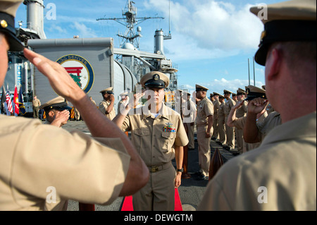 Chef nouvellement frocked Corpsman Hôpital Jose R. Rayos salue le commandant et chef principal de commande au premier maître de cérémonie l'épinglage à bord de l'avant-déployés de transport amphibie USS Denver dock (9 LPD). Denver est en patrouille avec les Banque D'Images