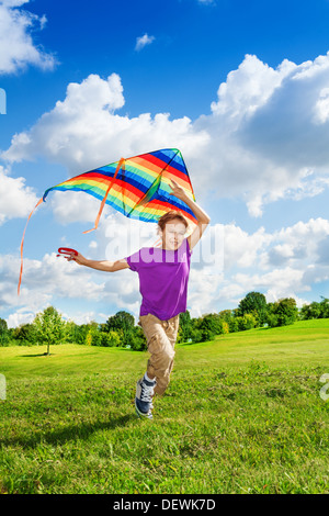 Happy 8 ans beau garçon s'exécutant dans le domaine avec un grand cerf-volant de couleur Banque D'Images