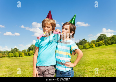 Portrait de deux garçons sur d'anniversaire s'amusant avec soufflant dans crécelle bruyamment Banque D'Images