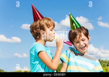 Deux garçons sur d'anniversaire s'amusant avec soufflant dans crécelle bruyamment Banque D'Images