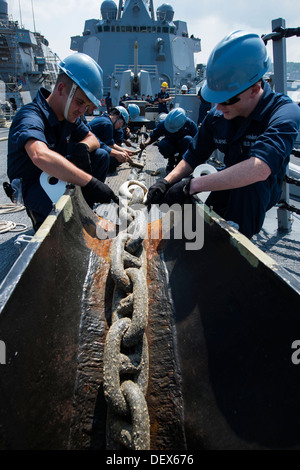 Les marins à bord de la classe Arleigh Burke destroyer lance-missiles USS Preble (DDG 88) gratter les balanes sur une chaîne d'ancre sur le Banque D'Images