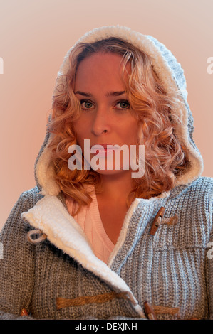 Portrait de la jeune femme portant jersey gris avec capot, sur un fond neutre dégradé Banque D'Images