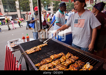 Griller les brochettes de poulet homme sur la grille du barbecue au festival en plein air - USA Banque D'Images