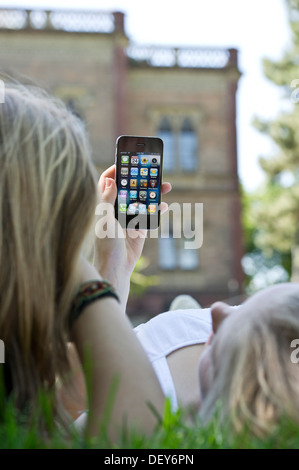 Deux jeunes femmes avec un smartphone, allongé sur un pré Banque D'Images