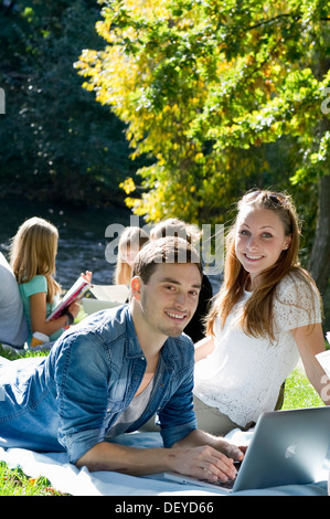 Les étudiants avec un ordinateur portable et des livres sur un pré, Freiburg im Breisgau, Bade-Wurtemberg Banque D'Images