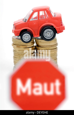 Miniature de voiture sur une pile de pièces, image symbolique pour les péages de voiture Banque D'Images
