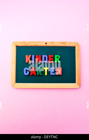 La maternelle, écrit en lettres magnétiques colorés sur une commission scolaire Banque D'Images