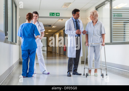 Infirmier brancardier poussant gurney lit dans un couloir de l'hôpital avec les médecins et les patients de sexe féminin senior Banque D'Images