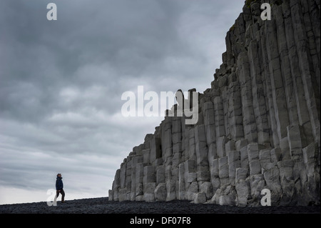L'homme à la recherche de colonnes de basalte, la plage de Reynisfjara qui jouit d'une plage de sable noir près de Vik í Mýrdal, côte sud, Islande, Europe Banque D'Images