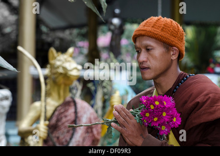 Le moine bouddhiste holding Flowers lors d'une collection d'aumône matin, temple et monastère de Wat Phra Thong Archa ou Golden Horse Banque D'Images