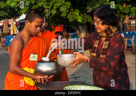 Matin l'aumône ronde, un jeune moine bouddhiste de l'école un monastère tenant une mendicité, de réception ou d'une offre de riz Banque D'Images