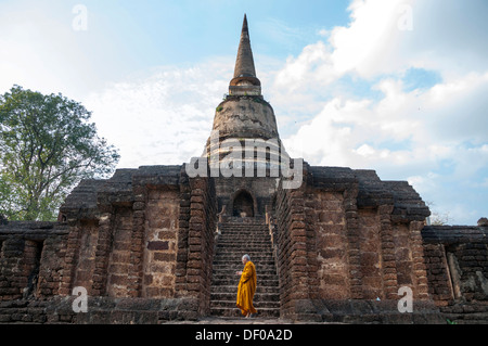 Priant le moine bouddhiste, latérite chedi, escaliers, vieux murs, s'est temple de Wat Chang Lom, le parc historique de Si Satchanalai Banque D'Images